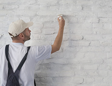 A painter filling in spots on a new brick paint job.