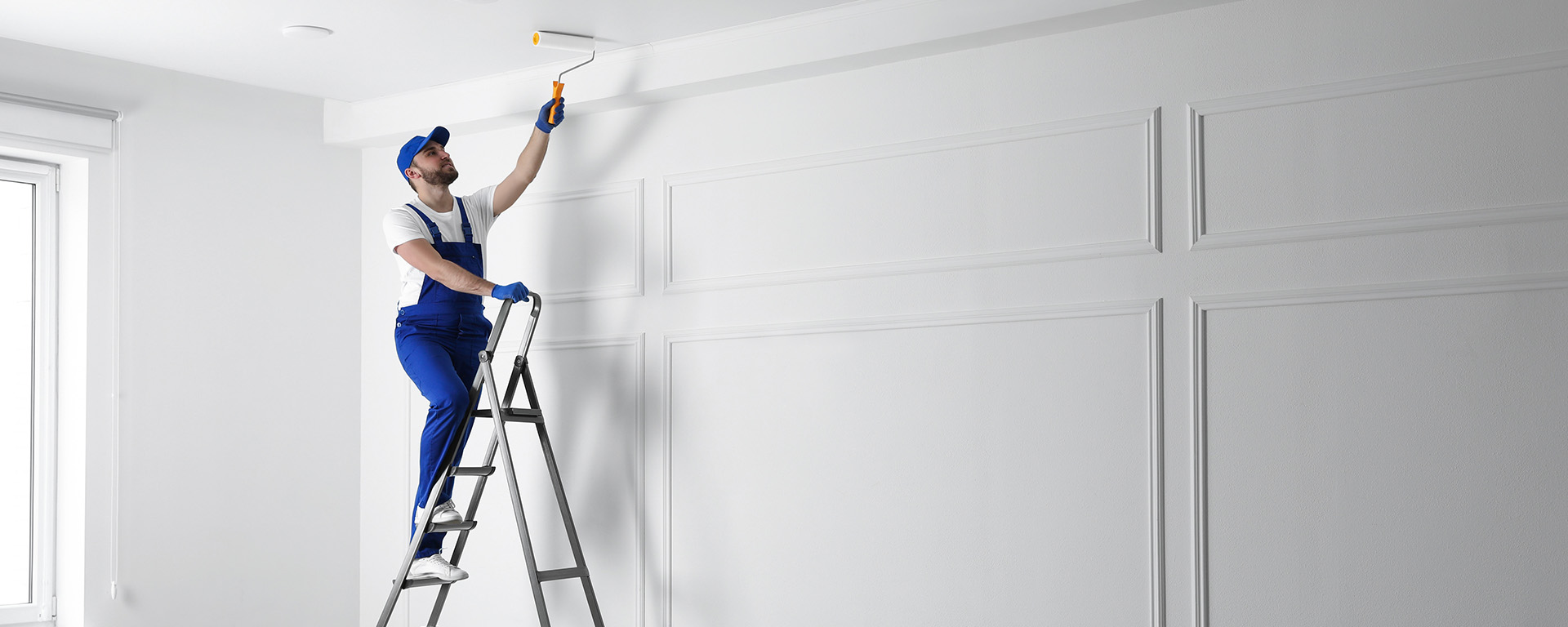 Photo of a professional painter on the inside of a home painting a dining room./